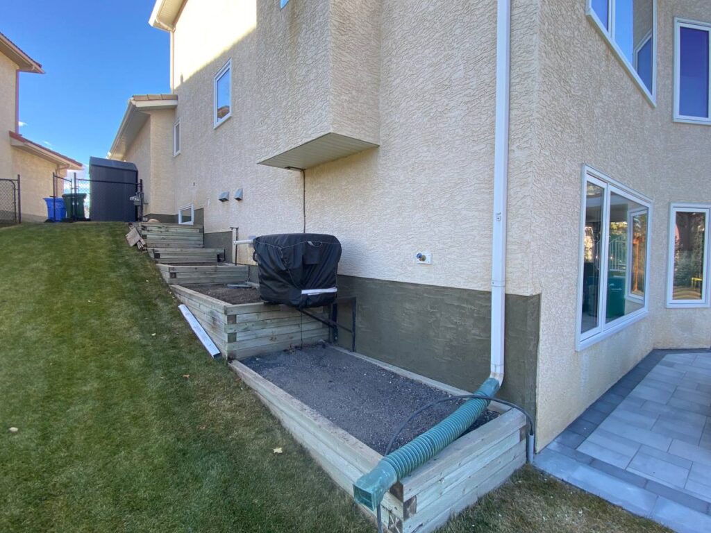 Repaired foundation parging and stucco along the side of a home
